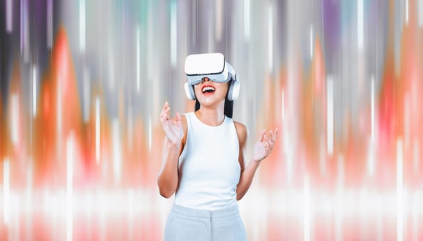 Female standing and wearing white VR headset and white sleeveless connect metaverse, future technology creating cyberspace community. She enjoy look fantasy abstract light around her. Hallucination.