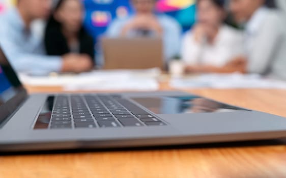 Closeup focused laptop with blurred background of business people using laptop computer to analyze financial data or data analysis display on screen background. Meticulous