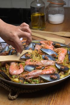 Cooking paella with shrimp and mussels using a wooden utensil in a home kitchen, typical Spanish cuisine, Majorca, Balearic Islands, Spain,