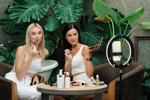 Two beautiful content creator making natural beauty and cosmetic tutorial on green plant garden video. Beauty blogger showing how to beauty care to social medial audience using selfie stick . Blithe