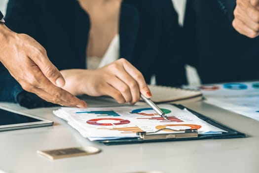 Businessman and businesswoman in meeting working with many financial statement document on desk. Concept of busy business profit analysis and brainstorm. Close up shot at people hands and papers. uds