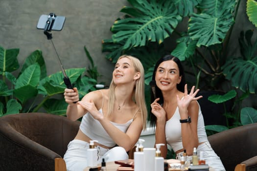 Two beautiful content creator making natural beauty and cosmetic tutorial on green plant garden video. Beauty blogger showing how to beauty care to social medial audience using selfie stick . Blithe