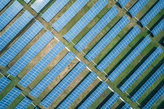 Aerial top down shot of solar panels farm on the green field. Renewable alternative green energy concept.