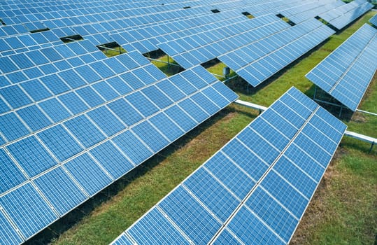 Aerial shot of solar panels farm on the green field. Renewable alternative green energy concept.