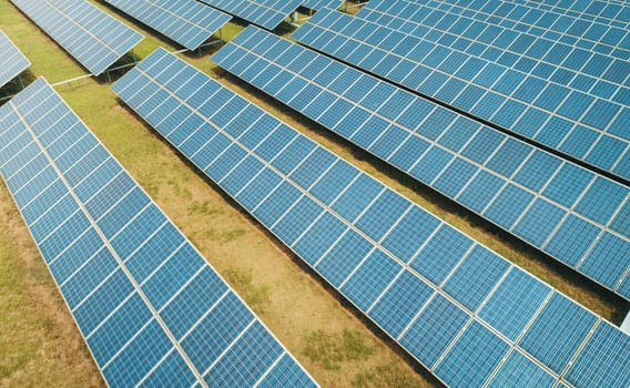 Aerial shot of solar panels farm on the green field. Renewable alternative green energy concept.