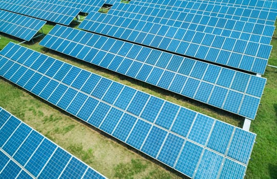 Aerial shot of solar panels farm on the green field. Renewable alternative green energy concept.