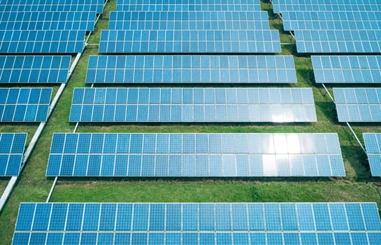 Aerial shot of solar panels farm on the green field. Renewable alternative green energy concept.