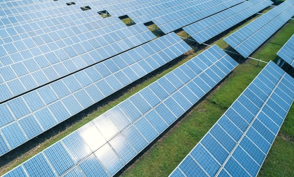 Aerial shot of solar panels farm on the green field. Renewable alternative green energy concept.