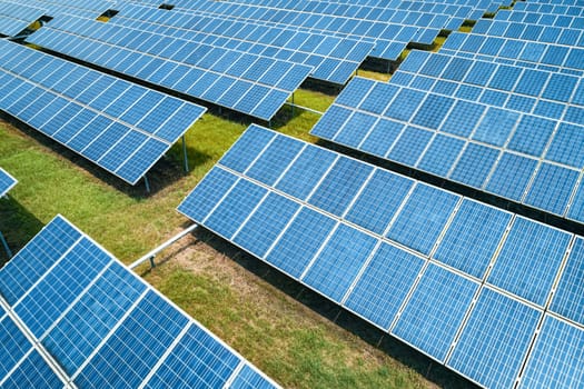 Aerial shot of solar panels farm on the green field. Renewable alternative green energy concept.