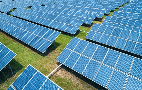 Aerial shot of solar panels farm on the green field. Renewable alternative green energy concept.