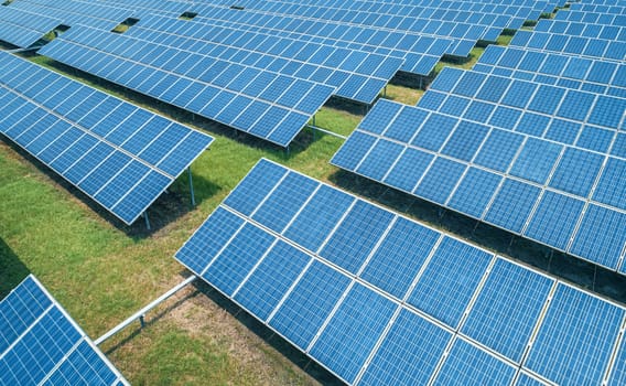 Aerial shot of solar panels farm on the green field. Renewable alternative green energy concept.