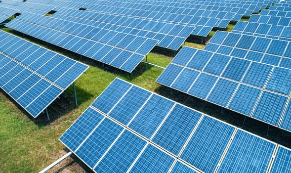 Aerial shot of solar panels farm on the green field. Renewable alternative green energy concept.