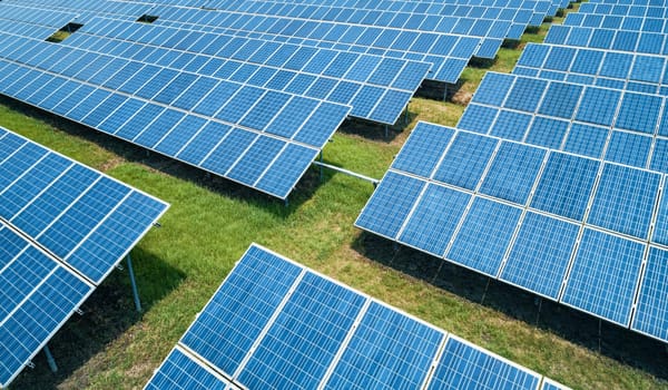 Aerial shot of solar panels farm on the green field. Renewable alternative green energy concept.