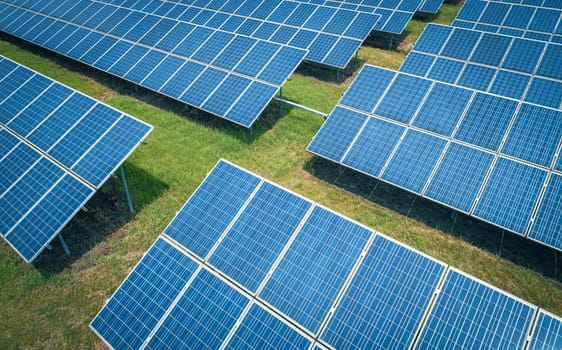 Aerial shot of solar panels farm on the green field. Renewable alternative green energy concept.