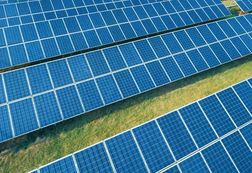 Aerial shot of solar panels farm on the green field. Renewable alternative green energy concept.