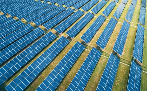 Aerial shot of solar panels farm on the green field. Renewable alternative green energy concept.