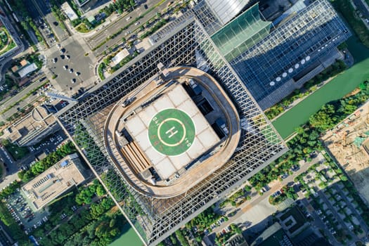 Aerial drone view of helipad on the roof of a skyscraper in downtown.