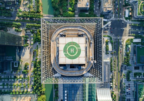 Aerial drone view of helipad on the roof of a skyscraper in downtown.