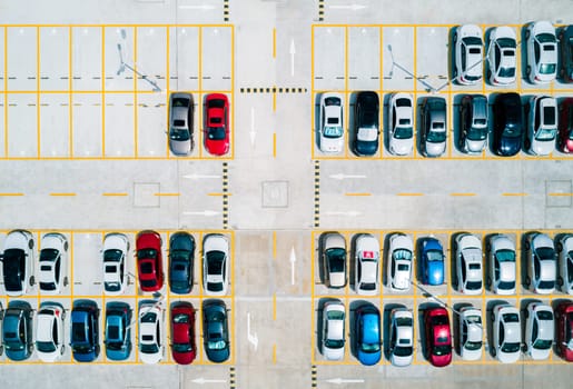 Aerial top down view a parking lot with cars of different colors.
