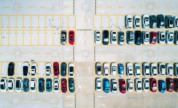 Aerial top down view a parking lot with cars of different colors.