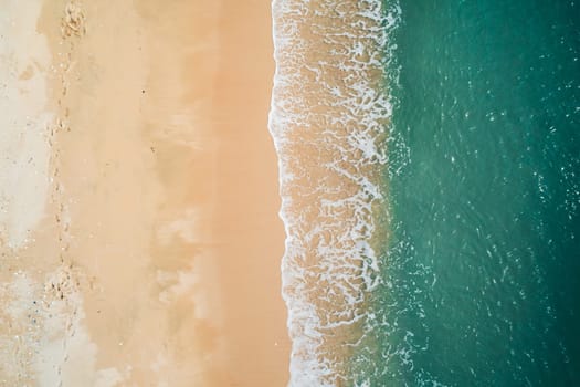 Aerial top down view of turquoise ocean wave reaching the coastline.