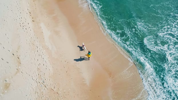 Aerial high angle shot of young woman walking with the dog along the seaside. Stunning seascape.