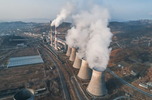 Aerial view of an industrial zone pipes pouring thick white smoke. Thick smoke plumes. Thermal power plant pipes, air pollution.