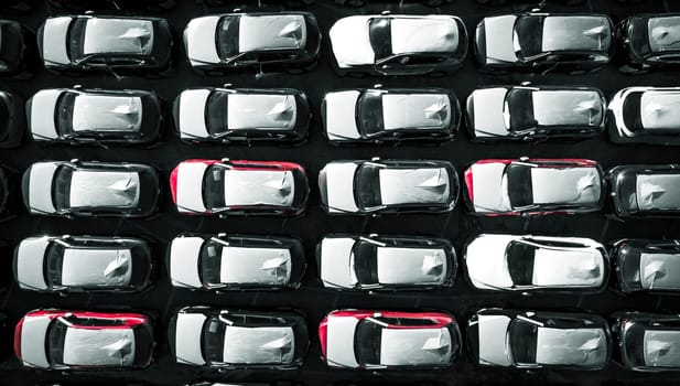 Aerial top down view of new cars parked in car parking lot. Car dealer parking lot full of new automobiles. New cars lined up for import and export business.