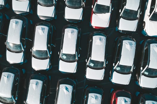 Aerial top down view of new cars parked in car parking lot. Car dealer parking lot full of new automobiles. New cars lined up for import and export business.