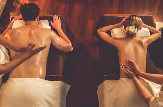 Top view couple customer enjoying relaxing anti-stress spa massage and pampering with beauty skin recreation leisure in warm candle lighting ambient salon spa at luxury resort or hotel. Quiescent
