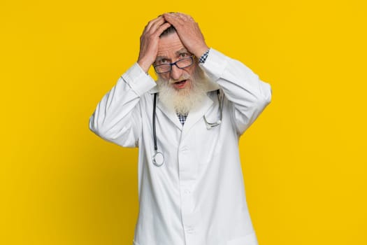 Senior doctor cardiologist old man feeling hopelessness and loneliness, nervous breakdown, loses, bad fortune loss unlucky news, fail. Apothecary pharmacy grandfather isolated on yellow background