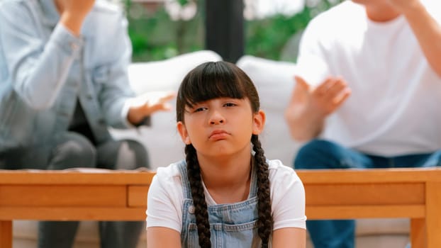 Stressed and unhappy young girl crying and trapped in middle of tension by her parent argument in living room. Unhealthy domestic lifestyle and traumatic childhood develop to depression. Synchronos