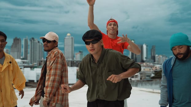 Skilled multicultural street dancing group pose at camera at roof top while moving to the rhyme and music. Young people or teenager moving to funky music, break dance. Outdoor sport 2024. Endeavor.