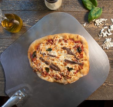 Top view of anchovy pizza on meatal pizza peel.