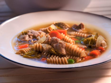 Side view of chicken noodle soup on natural wood surface