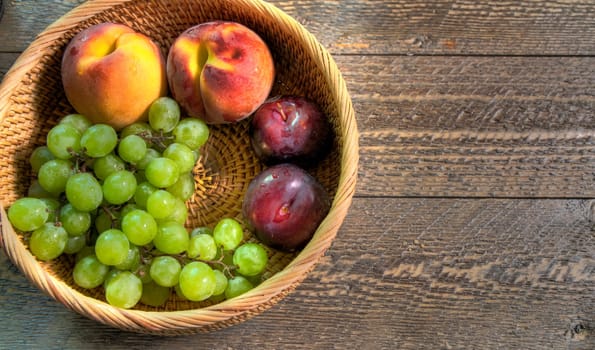Top view of fruit in wicker basket on natural wood surface