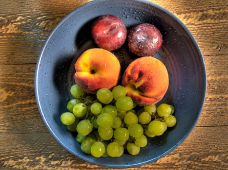 Top view of fruit in blue ceramic bowl on natural wood surface