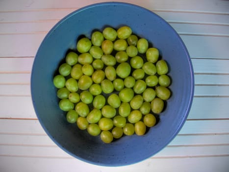Top view of bowl of grapes on natural white wood surface