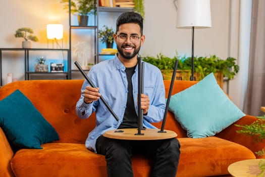 Happy Indian man finishing assembling furniture at home. Successful table desk collect, repair fixing. Arabian guy after moving into new apartment. Advertisement of a furniture store. Mortgage.