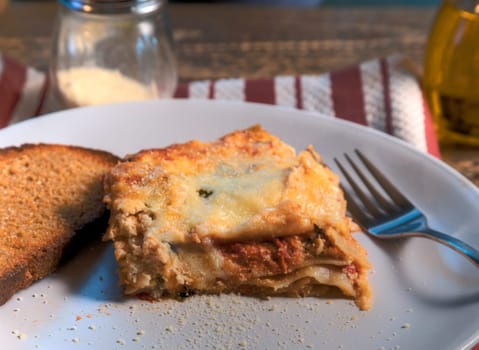 Side view of a serving of lasagna on natural wood surface