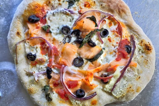 Smoked Salmon Pizza fresh out of the oven on its pizza peel.
