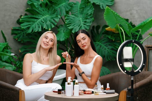 Two beautiful content creator making natural beauty and cosmetic tutorial on green plant garden video. Beauty blogger showing how to beauty care to social medial audience using selfie stick . Blithe