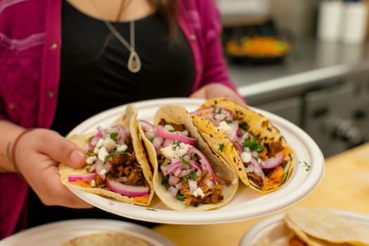 A plate of tacos is being served by a woman.