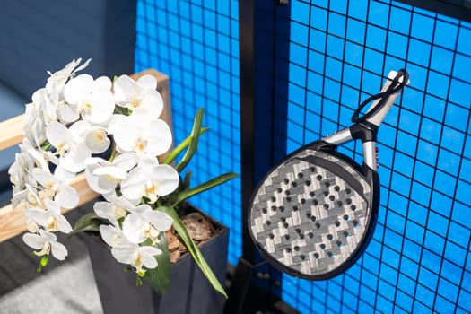 Closeup view of a paddle racket in a padel tennis court near the net. Sport, health, youth and leisure concept. Sporty equipment. White lines in background. High quality photo