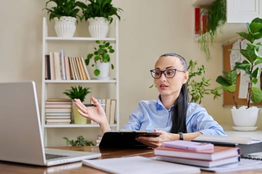 Woman psychologist mental therapist counselor social worker working remotely using computer for online therapy meeting. Female with clipboard look talk at laptop. Technology psychology psychotherapy