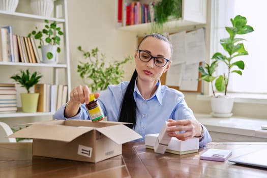 Satisfied female consumer buyer sitting at home unpacking cardboard box with online purchases. Woman unpacking boxes with cosmetics care products vitamins perfumes. Delivery by mail, online store