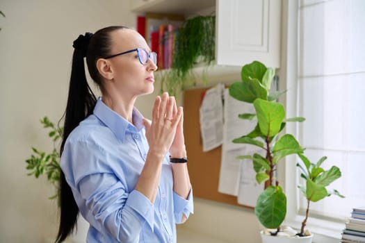 Serious thoughtful woman in her 30s looking out the window. Emotions, lifestyle, health, people concept