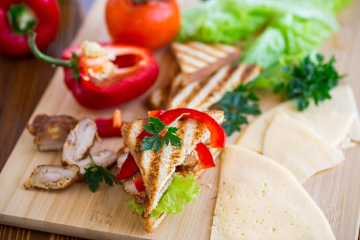 fried toast with chicken, salad, greens on a wooden table .
