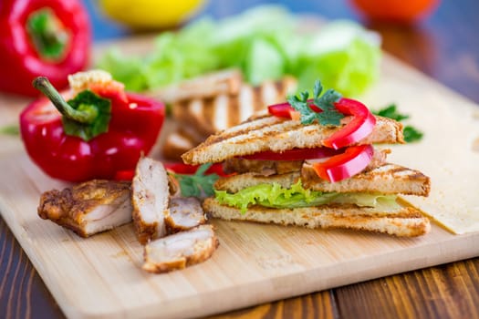 fried toast with chicken, salad, greens on a wooden table .