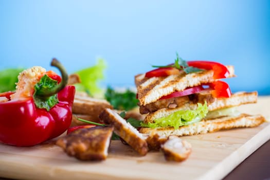 fried toast with chicken, salad, greens on a wooden table .